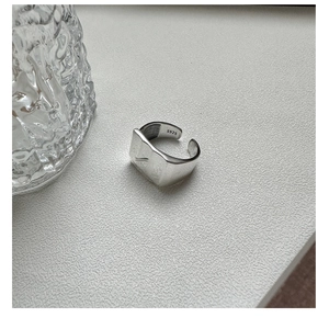 Close-up of S925 sterling silver open ring with irregular square texture on sand surface