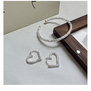 Macro shot of S925 sterling silver set featuring baroque floral texture and heart earrings