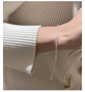 Détail macro du bracelet minimaliste en argent S925 sur un pull en maille blanche