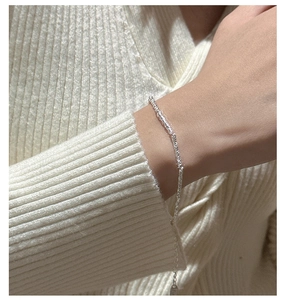 Détail du bracelet en argent S925 avec texture martelée porté sur un pull en maille