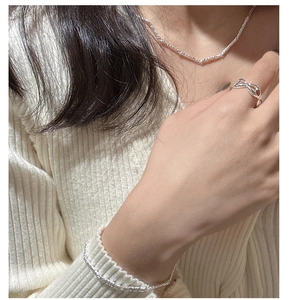 Détail d'un bracelet et d'une bague en argent S925 minimaliste portés par un mannequin