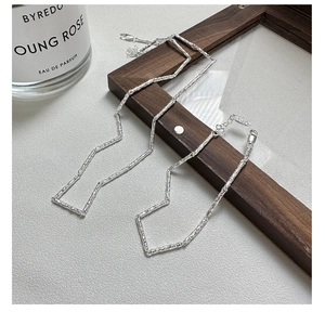 Détail de la chaîne en argent sterling S925 avec texture martelée sur fond de bois sombre