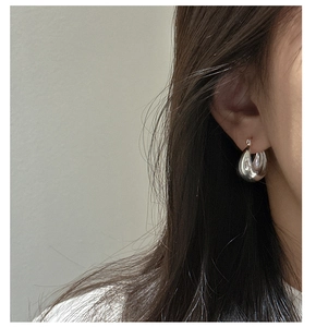 Close-up of teardrop wide silver earrings with high-polish finish on a female model