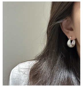Close-up of polished S925 silver teardrop hoop earrings on a model with a minimalist style