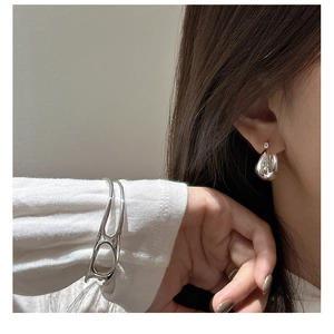 Detail view of S925 sterling silver teardrop earrings and a streamlined cuff bracelet