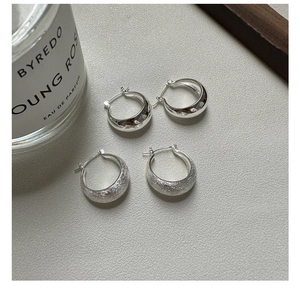 Macro shot of silver S925 hoop earrings with polished and brushed texture finishes