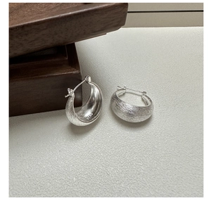 Close-up of S925 sterling silver earring featuring brushed texture and metal hallmark