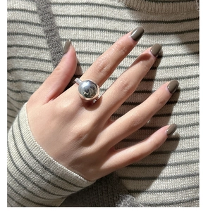 Macro shot of minimalist high-polished silver spherical ring on fingers