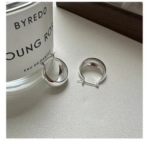 Detailed view of chunky silver-colored C-shaped hoop earrings with a high-polished finish