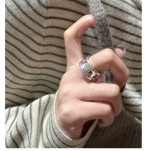 Close-up of irregular chunky silver ring worn on model finger with cozy background