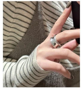 Close-up of a wide irregular liquid metal silver ring worn on a finger