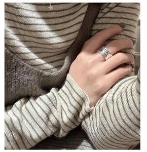 Close-up of irregular textured wide S925 silver ring on hand with autumn outfit