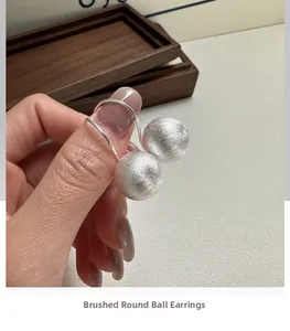 Detailed macro view of brushed silver sphere earrings with matte texture finish