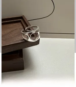 Macro shot of silver hollow geometric ring displayed on a dark wooden ring box