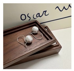Macro detail of S925 sterling silver brushed ball drop earrings with elegant hooks