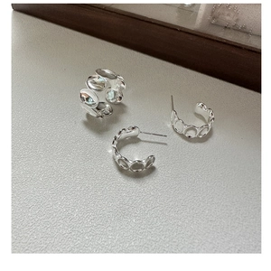 Makro-Detail des silbernen Schmucksets mit ovalem strukturiertem Ring und Ohrringen