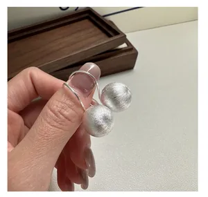 Detail showing brushed silver sphere earrings with minimalist textured metal finish