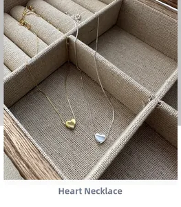 Vue détaillée de colliers cœur minimalistes en or et argent dans une boîte à bijoux en bois