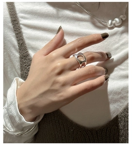 Detail of a wide hollowed-out silver ring worn by a model with minimalist modern jewelry