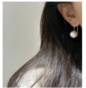 Detail of S925 sterling silver ball earrings with brushed texture on female model