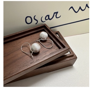 Macro detail of S925 sterling silver ball earrings featuring a brushed texture finish
