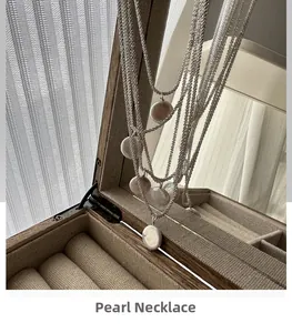 Detail of layered S925 silver necklace featuring a flat baroque pearl on a wooden box
