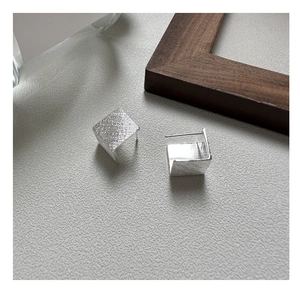 Détail de boucles d'oreilles carrées en argent S925 mat avec texture en métal brossé