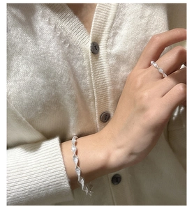 Detail of twisted S925 sterling silver bracelet and ring set on model's wrist