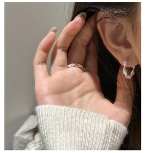 Close-up of S925 sterling silver wavy twisted bangle and ring on model with knit sweater