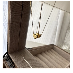 Gros plan d'un pendentif cœur doré poli suspendu sur une boîte à bijoux en bois vintage