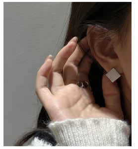 Détail macro de boucles d'oreilles carrées en argent S925 avec une finition brossée