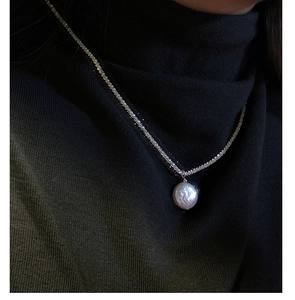 Detail of a sparkling Baroque pearl necklace on a black turtleneck sweater