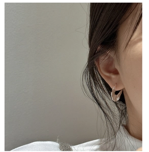 Close-up of a model wearing a gold fan-shaped textured earring with a shell-like design