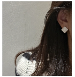 Détail de boucles d'oreilles carrées en argent mat avec texture brossée sur le mannequin