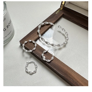 Close-up of S925 sterling silver twisted bangle and earrings with wave texture detail