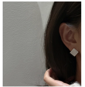 Gros plan de boucles d'oreilles carrées minimalistes en argent S925 à texture brossée