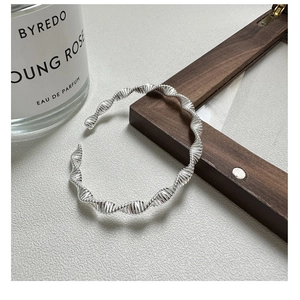 Detailed shot of S925 sterling silver twisted bangle showing modern wavy spiral texture
