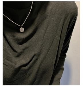 Close-up of S925 sterling silver chain with a baroque button pearl pendant on a black shirt