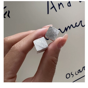 Gros plan de boucles d'oreilles carrées en argent 925 avec une finition métal brossé