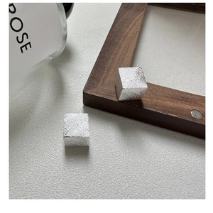 Détail macro de boucles d'oreilles cubes en argent avec texture en métal brossé
