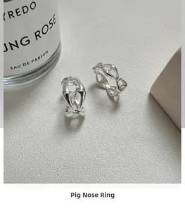 Macro detail of S925 sterling silver pig nose ring with polished finish on grey sand