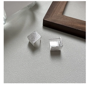 Détail des boucles d'oreilles géométriques en argent S925 avec une texture brossée élégante