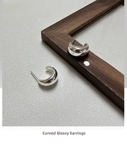 Detail of S925 sterling silver arc hoop earrings with smooth surface and bead texture