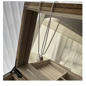 Detail of a heart-shaped purple pearl pendant on a S925 silver chain in a wooden box