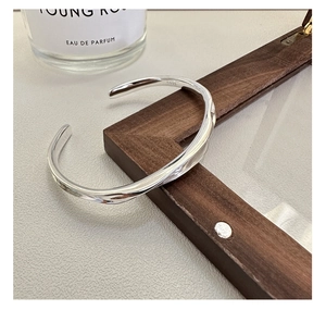 Detailed view of an irregular wavy S925 sterling silver cuff bracelet on wood