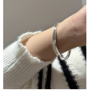 Close-up of a 925 sterling silver irregular streamline cuff bracelet on a female wrist