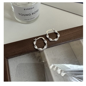Makroansicht von S925 Sterling Silber Creolen mit Wellenstruktur auf Holztablett