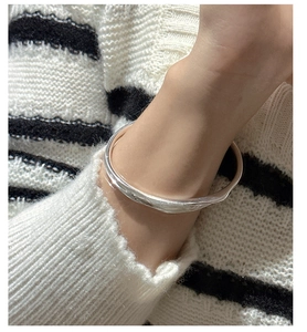 Detailed close-up of a minimalist 925 silver irregular streamlined bangle on wrist