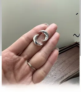 Vue détaillée de boucles d'oreilles lune en argent avec une finition miroir polie en main