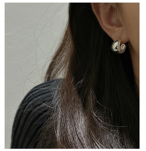 Close-up of chunky silver hoop earrings with bead trim on model with black outfit